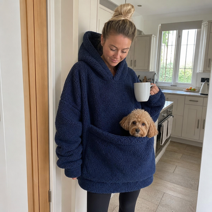 Woman in a kitchen wearing the Joey hoodie, dog sitting in the front pouch